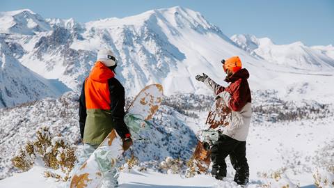 two friends walking in the snow ready to snowboard