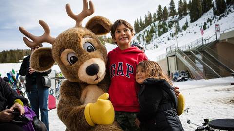 kids hugging June's mascot Bucky