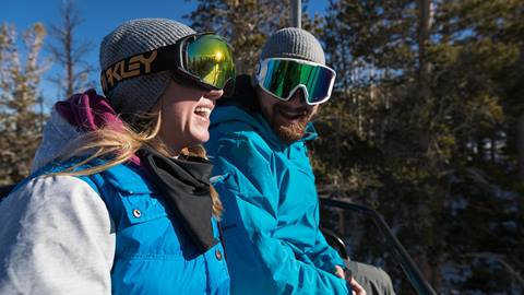 A happy couple riding a chairlift at June Mountain, enjoying the scenic views