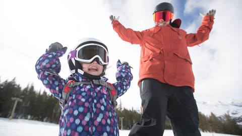 toddler skiing with hands in the air