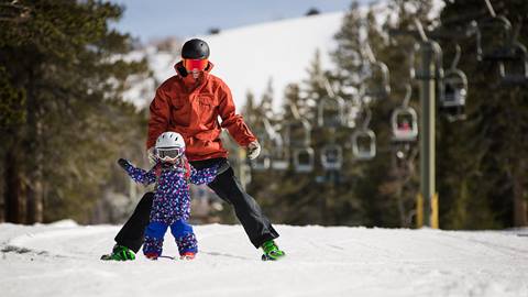 A father guides his daughter skiing at June Mountain